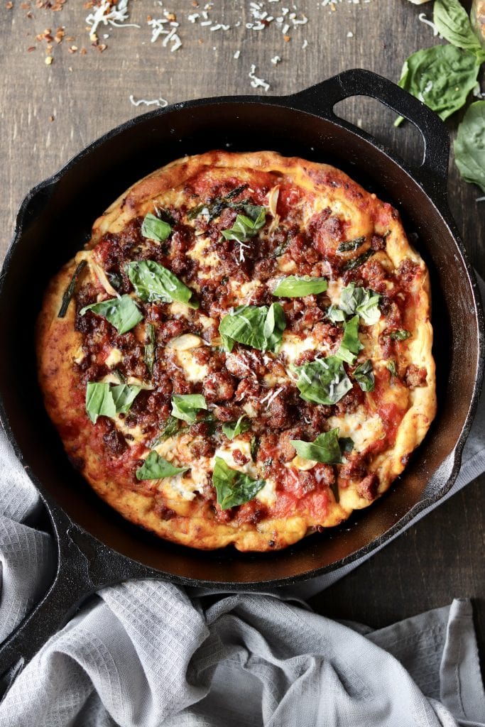 Pizza in a cast iron skillet with toppings. 