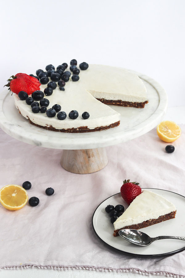 cheesecake on a pedestal with fruit.