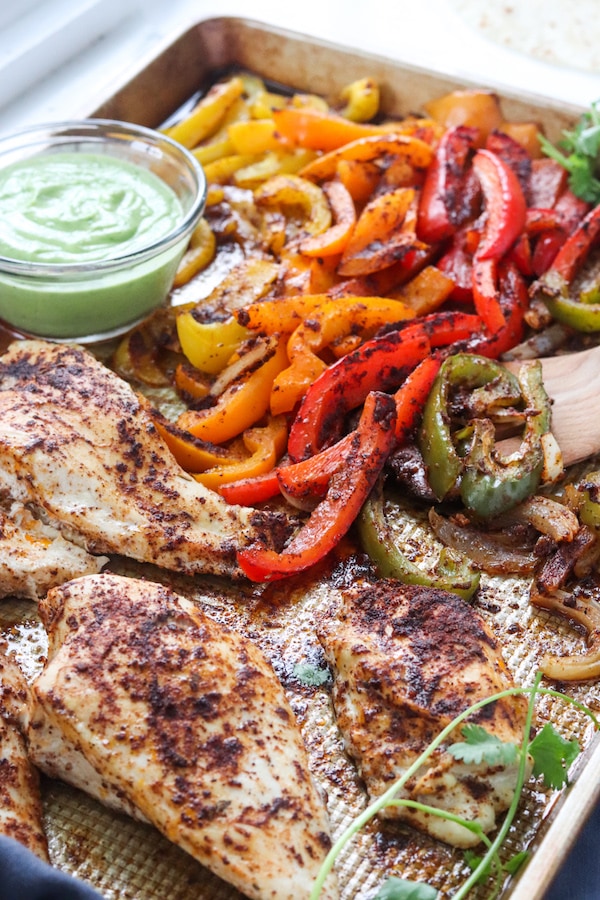 These one sheet pan chicken fajitas with avocado sauce can be made in under 30 minutes and is an easy clean up! Peppers, avocado and low sodium fajita seasoning makes for a heart healthy meal. | mealswithmaggie.com #hearthealthy #onesheetpandinner #onesheetpanchickenfajitas #avocadosauce #lowsodiumfajitas #quickandeasydinner #mealprep