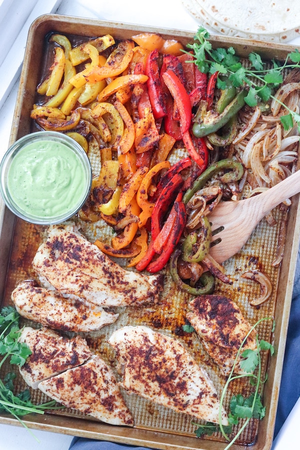 These one sheet pan chicken fajitas with avocado sauce can be made in under 30 minutes and is an easy clean up! Peppers, avocado and low sodium fajita seasoning makes for a heart healthy meal. | mealswithmaggie.com #hearthealthy #onesheetpandinner #onesheetpanchickenfajitas #avocadosauce #lowsodiumfajitas #quickandeasydinner #mealprep