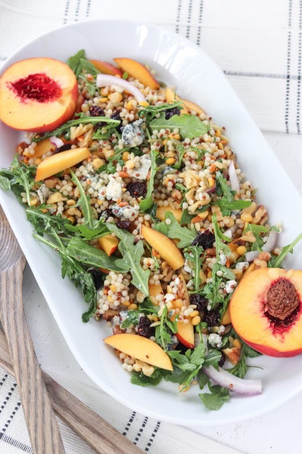 Salad served on a plate with peaches and dried cherries