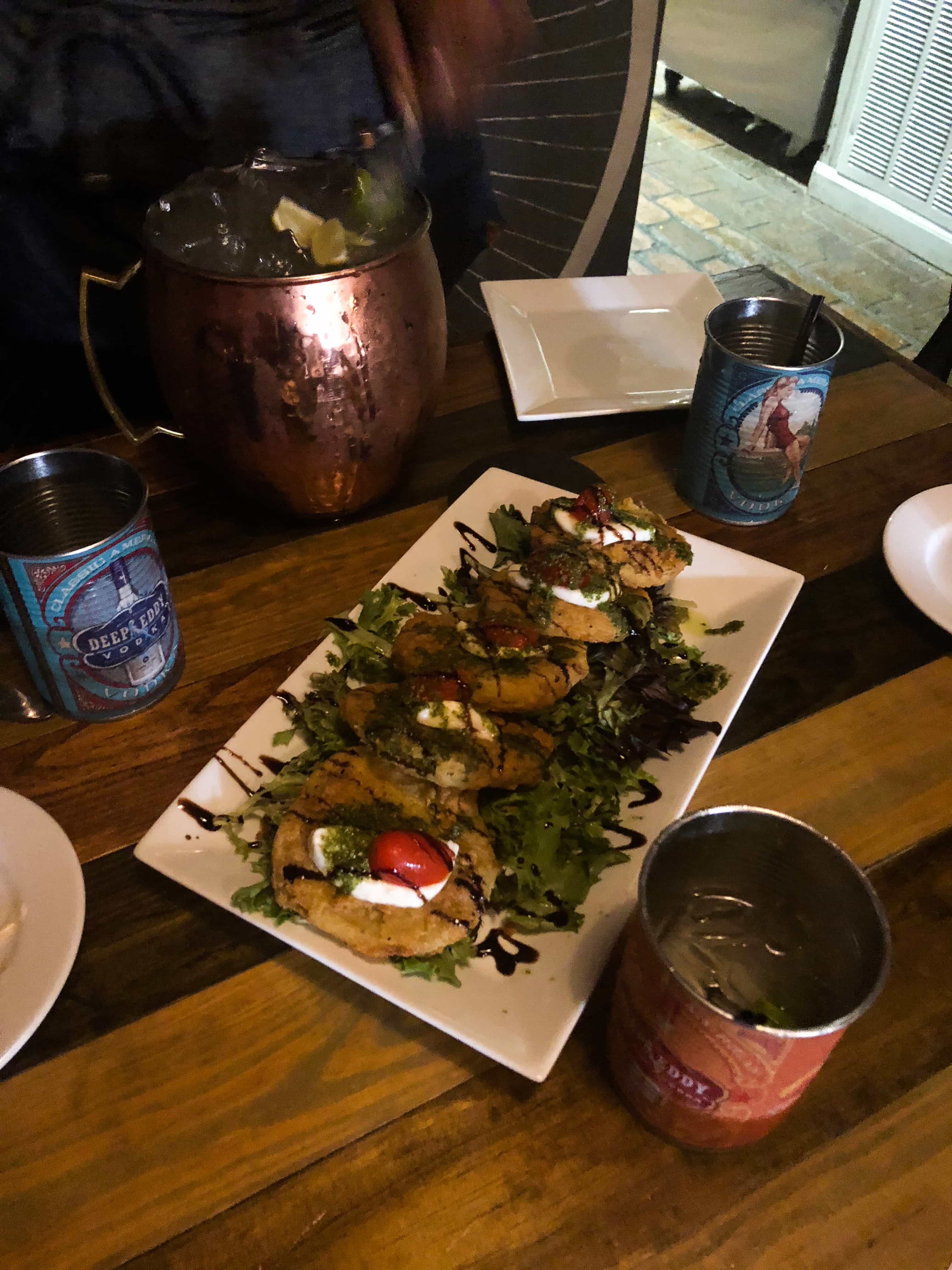 caprese salad on a plate with drinks.