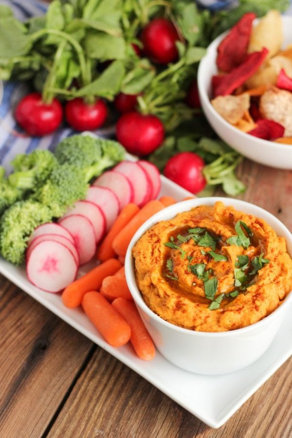 dip in a cup with vegetables next to it.